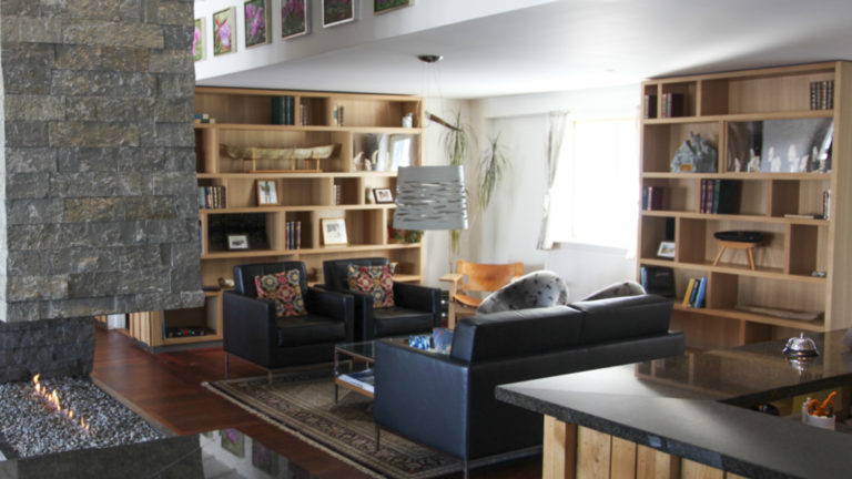 Lobby with fireplace, couch, coffee table, armchairs and bookcases in Hotel Angmagssalik in East Greenland