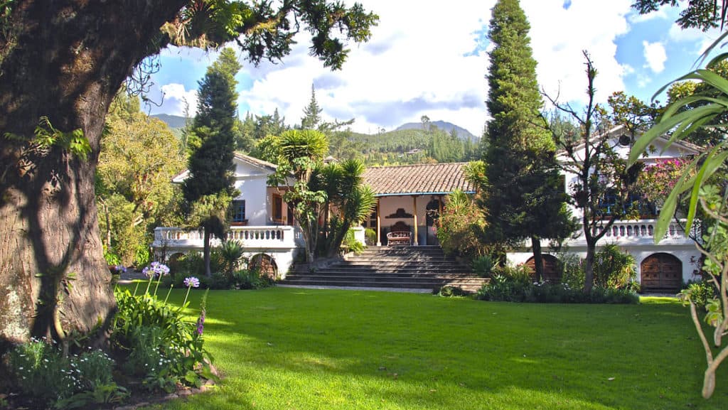 Exterior of Hacienda Cusin in Ecuador, with large lawn and local flora