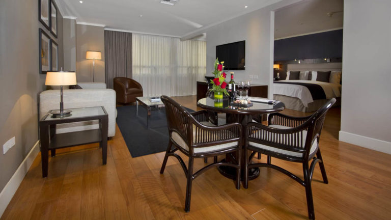 The leading suite at the Hotel Oro Verde in Guayaquil, Ecuador offers modern furniture, a seating area with a table, chairs, and a couch, and a large bed