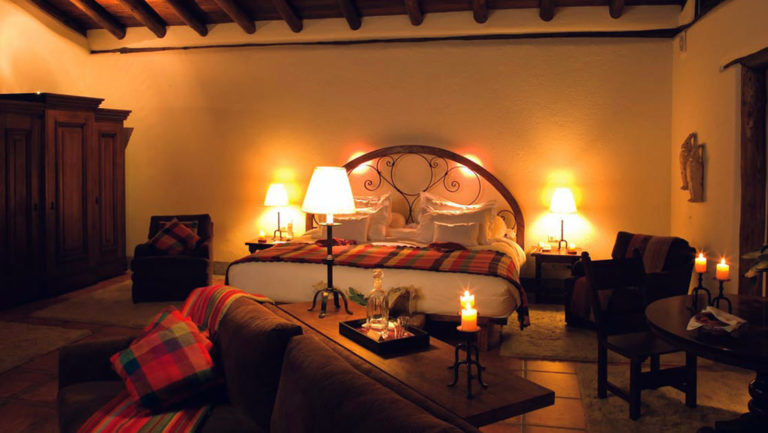 One of the rooms at the Inkaterra Machu Picchu Pueblo Hotel, with a king-sized bed, couch, and reading lights, designed with Andean style and the exquisite handicraft of local artisans and tasteful furnishings.