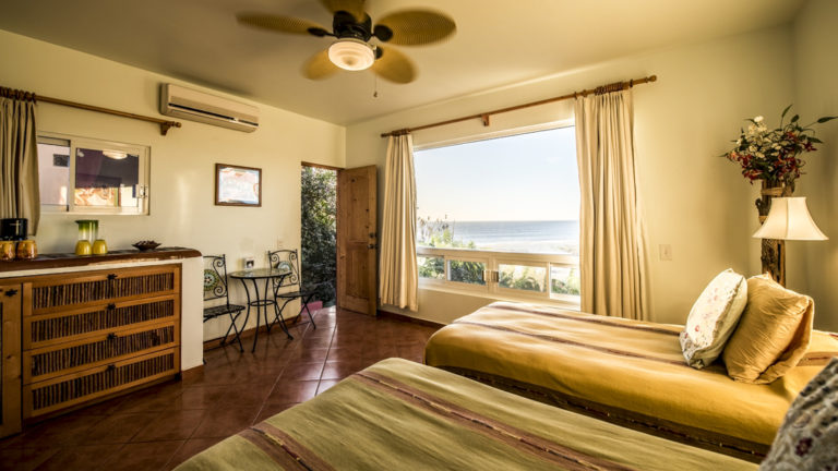 A room inside a private condo with two beds and a terrace overlooking the Pacific ocean at the boutique Baja hotel Los Colibris Casitas