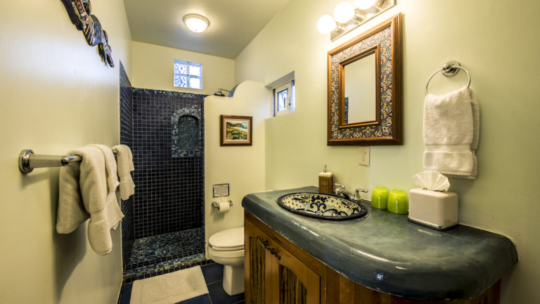 A bathroom inside a private condo with a vanity, mirror, sink, toilet, shower, and fresh towels at the boutique Baja hotel Los Colibris Casitas