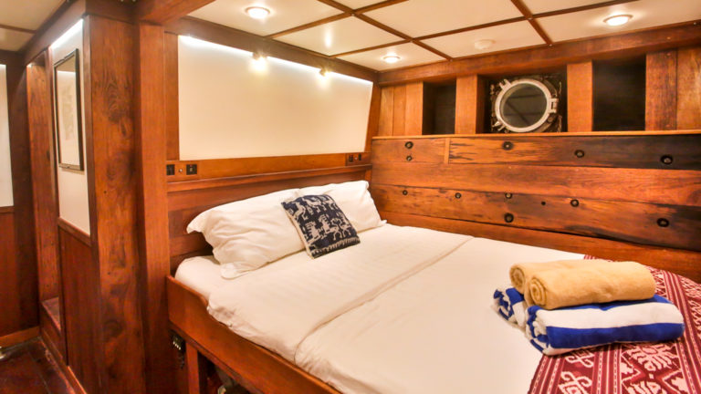 a room with wooden walls and a bed aboard the ombak putih