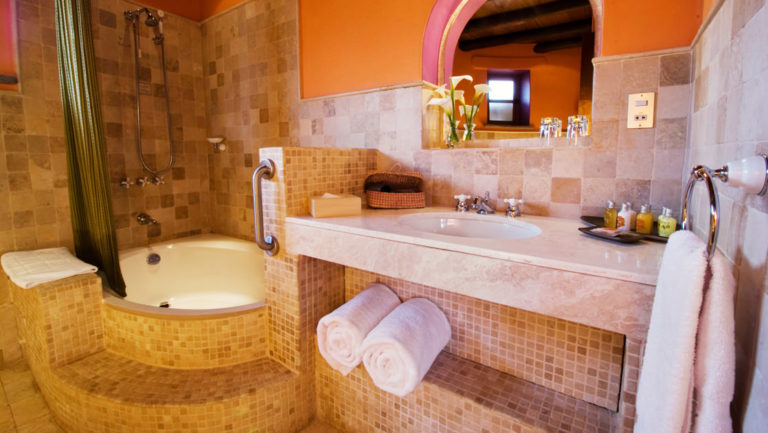 The bathroom inside a superior suite features a sink, vanity, mirror, toilet, and hot shower, with fresh towels, at Sol y Luna, a sustainable, luxury retreat in Urubamba, one hour’s drive from Cusco.