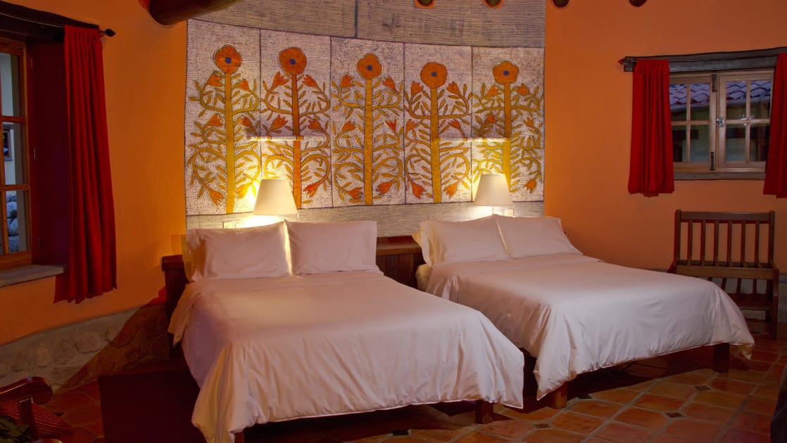 The superior casita room with two twin beds, decorative tiled walls, and reading lights at Sol y Luna, a sustainable, luxury retreat in Urubamba, one hour’s drive from Cusco.