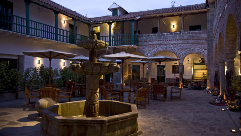 The fountain in the courtyard at Casa Andina Premium in Cusco, Peru, with an arched walkway and two story hotel for guests to relax.