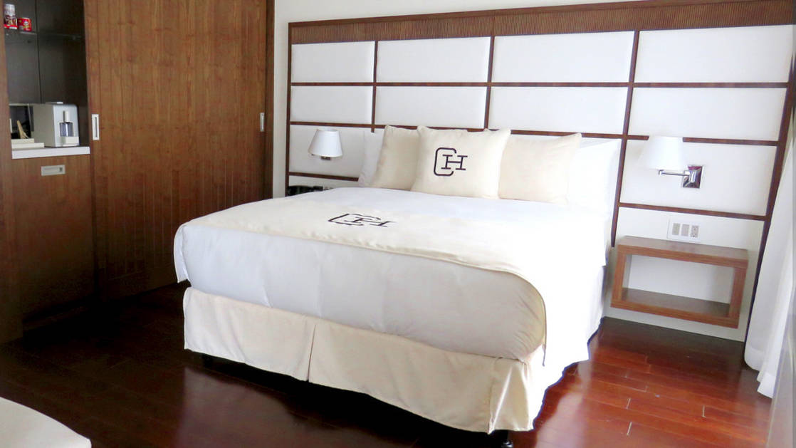 Large bed with wood detailing and kitchenette in the Presidential Suite at Central Hotel Panama in Panama City