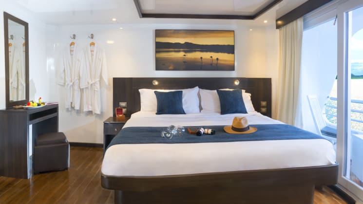 Cormorant stateroom with king bed, nightstand, sliding glass door and balcony.