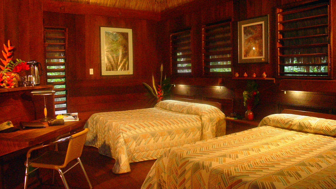 Inside one of the cabins at Lamanai Outpost, a sustainable eco-lodge in Belize, with two full beds and handcrafted furniture