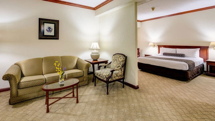 suite room at the las americas hotel in guatemala with two areas, one with a large king bed and one with a couch, table, chair and illuminated lamp