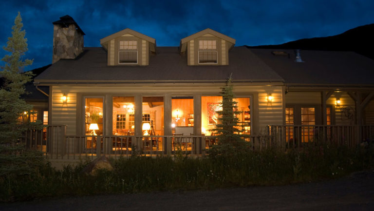 Lights glow from the windows of the North Face Lodge at night. The hotel is located within Denali National Park in Alaska.