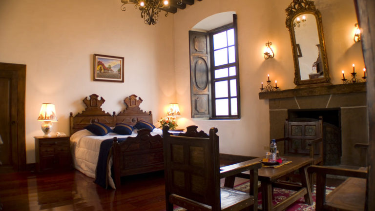 A room with a full bed, decorated in the colonial style of Antigua, inside the historic, renovated Hotel Posada Don Rodrigo