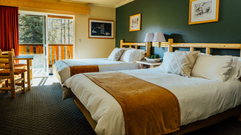 A standard room with two full beds and a private deck for guests to enjoy the Alaskan wilderness at the Seward Windsong Lodge, a stopover for exploring the Kenai Fjords National Park.