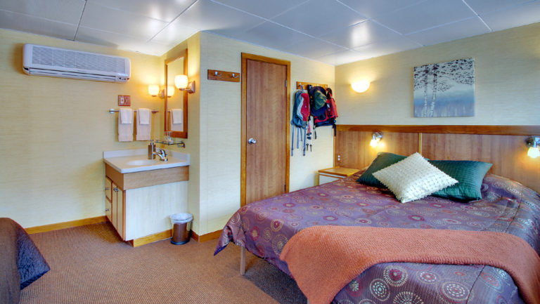 Admiral cabin aboard Wilderness Discoverer with queen bed and sink.