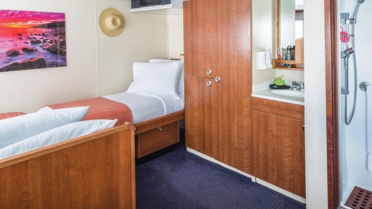 Two beds, closet, sink and shower in Category 3 cabin aboard National Geographic Sea Bird expedition ship
