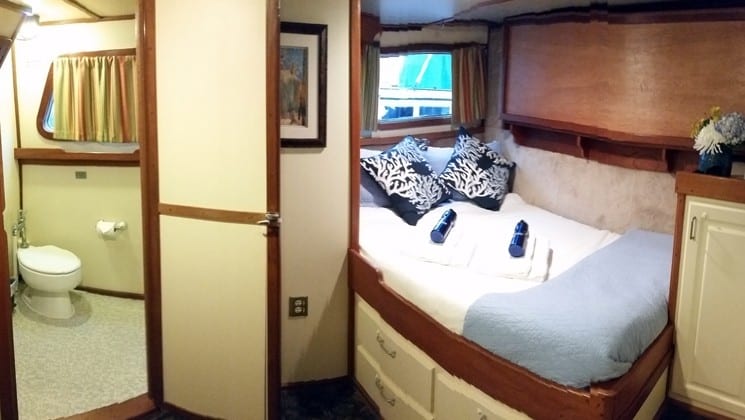 Cabin with bed, window, bathroom, toilet aboard Sikumi yacht in Alaska