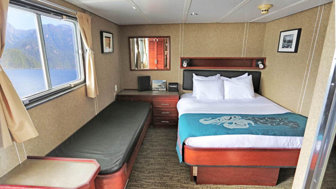 Deluxe stateroom with double bed, side couch, and window aboard Admiralty Dream