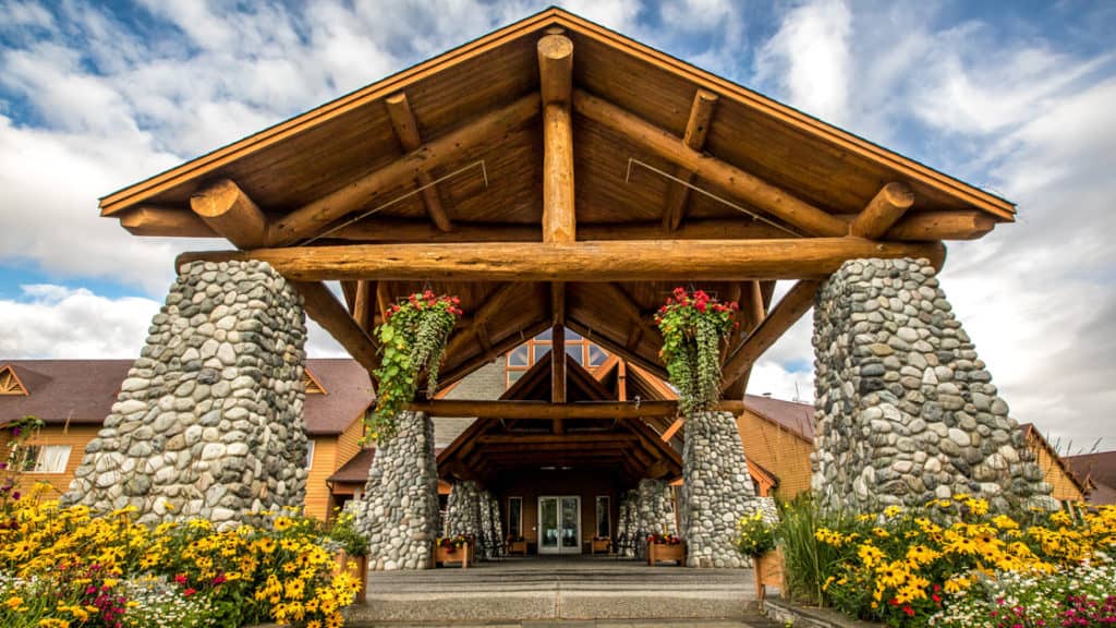 Exterior view of the front door with large stone pillars and A frame at Talkeetna Lodge in Alaska.