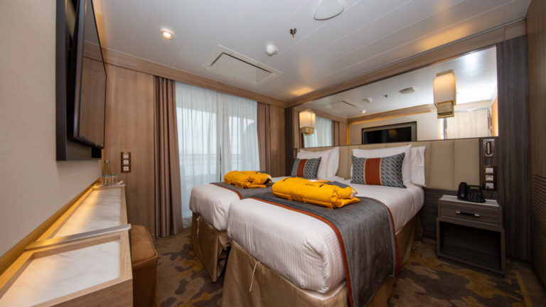 Owner's Suite aboard World Explorer with double bed, sitting area, 2 parkas, TV and balcony.