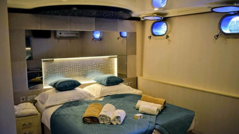 Lower Deck cabin with bed and two portholes aboard Ave Maria