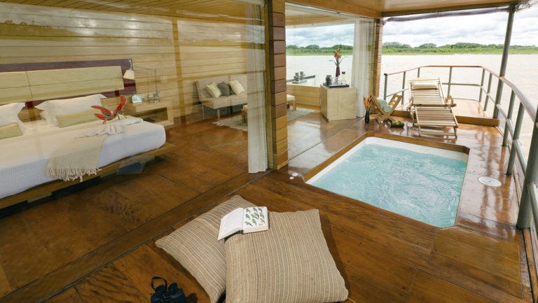 Deluxe Suite with bed, couch and private balcony with Jacuzzi aboard Delfin I on the Amazon River