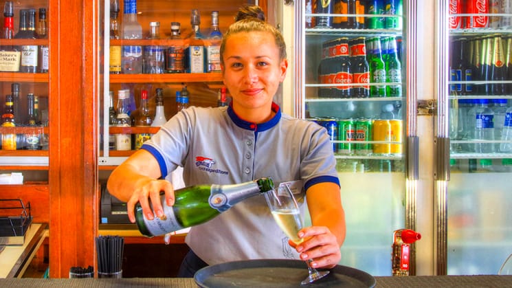 Woman pours a beer behind the bar aboard the Coral Expeditions II in Australia