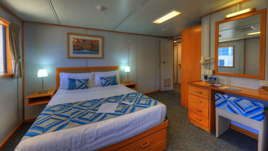 Upper Deck Stateroom aboard Coral Expeditions I with bed, desk, window, and doorway.