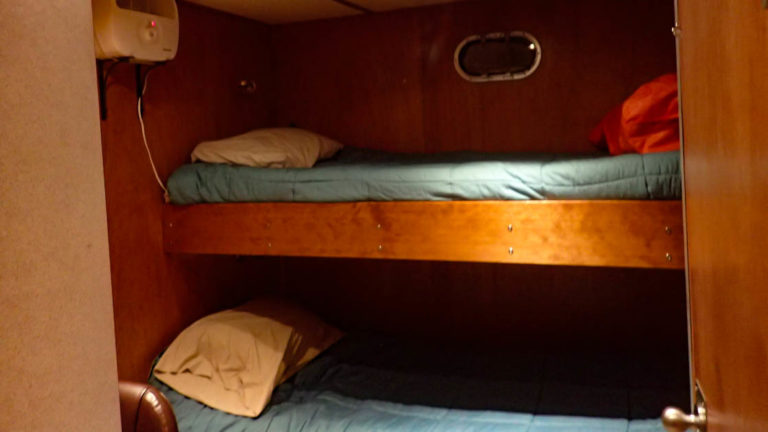 Dream Catcher stateroom with twin berth bunk beds and small porthole.