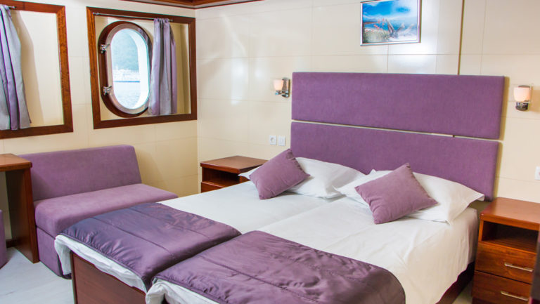 Small ship cruise Futura main deck cabin with double bed, 2 windows, seating area, nightstand, and night lights.