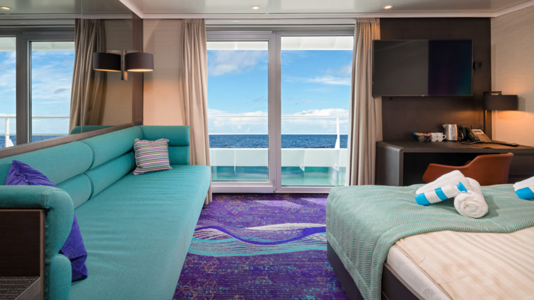 Grand Suite aboard Hondius and Janssonius polar small ships, with teal and purple accents, couch, double bed & balcony.