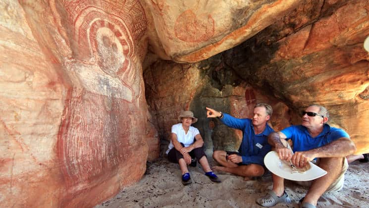 a guide points to indigenous cave art on a tour during the Kimberley - Cruising to the Australian Outback small ship cruise trip