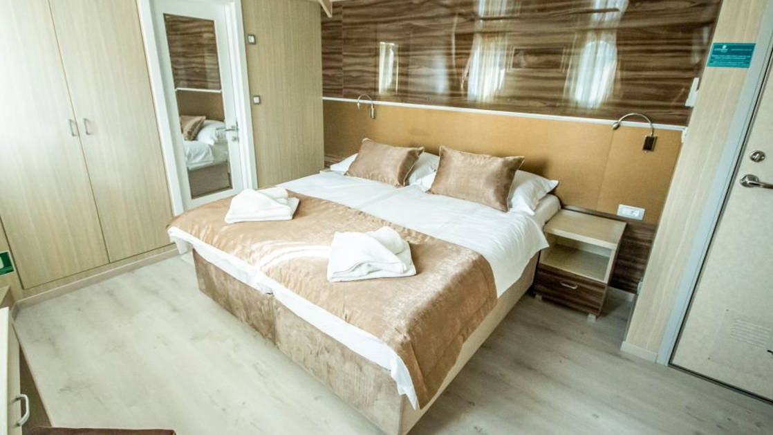 Markan Main Deck Cabin with double bed, bathroom, closet, nightstand, reading lights and small portholes.