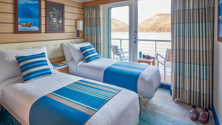 Two beds, sliding glass door and private balcony aboard National Geographic Venture expedition ship