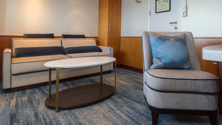 suite living room with a table, chair and couch aboard Ocean Adventurer