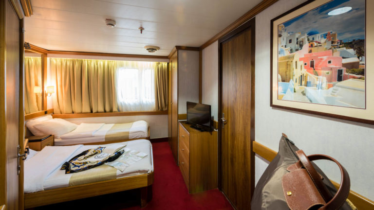 panorama luxury yacht cabin with two beds in front of a window and red carpet