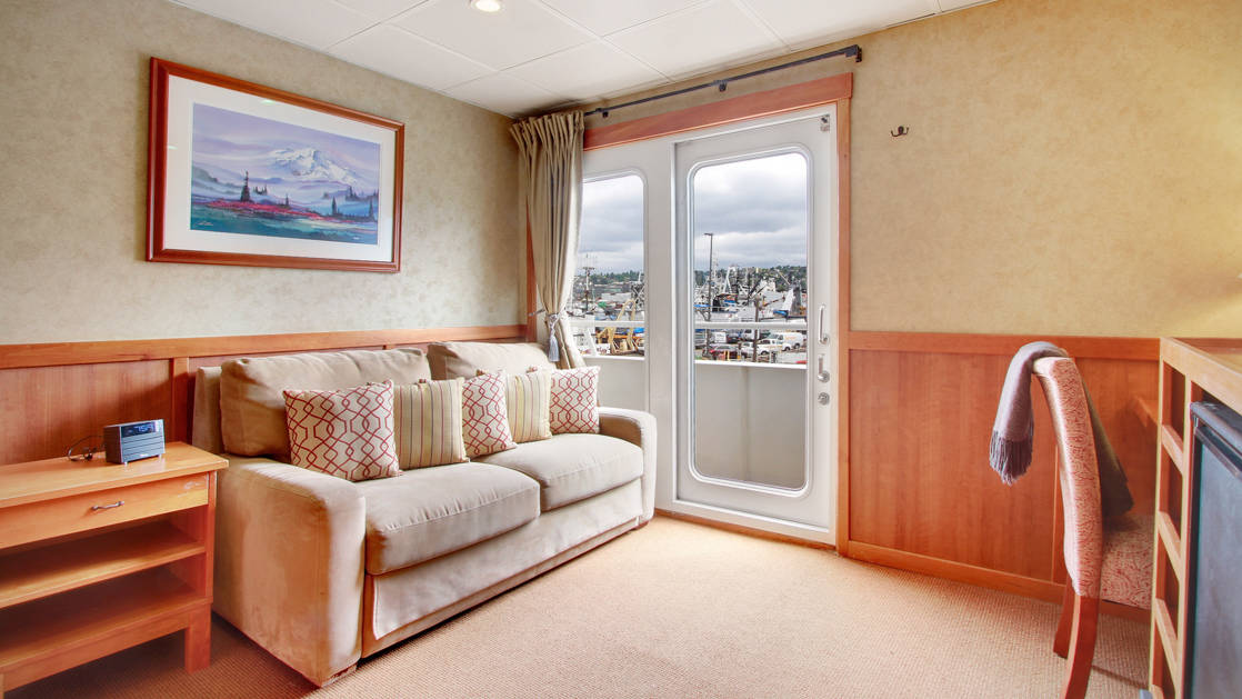 Seating area of commodore suite love seat, glass sliding doors, opening to adjoining room aboard the Safari Explorer Hawaii small ship