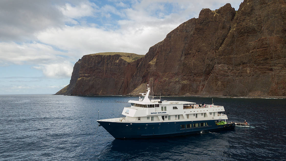 Safari Explorer Hawaii small ship cruising on a sunny day with large white clouds above.