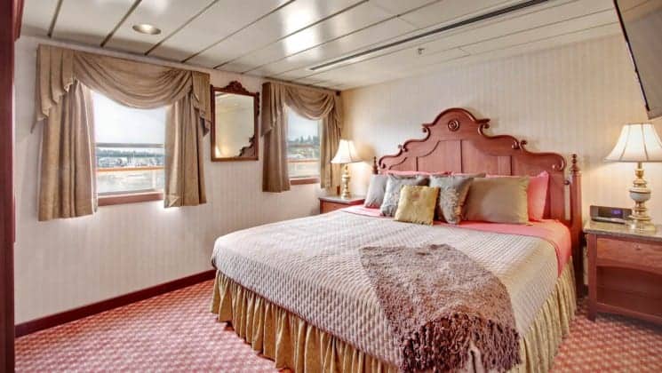 Large bed, two nightstands, two large windows is Owner's Suite aboard Wilderness Legacy expedition ship