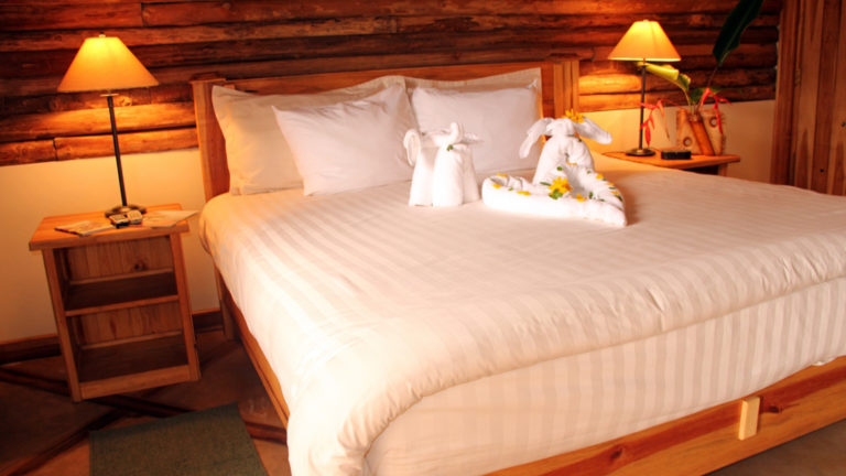 A room at Boquete Tree Trek resort with a large queen bed with whit linens.