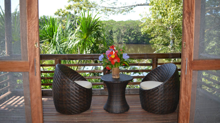 The private balcony of a superior suite overlooks Lake Garzacocha with panoramic jungle views, seating, table, fresh flowers at La Selva Amazon EcoLodge in Ecuador
