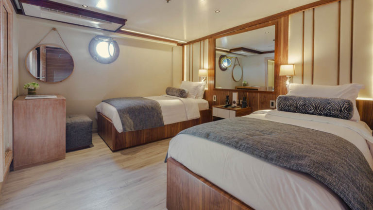 Evolution stateroom with twin beds, desk, nightstand and porthole.