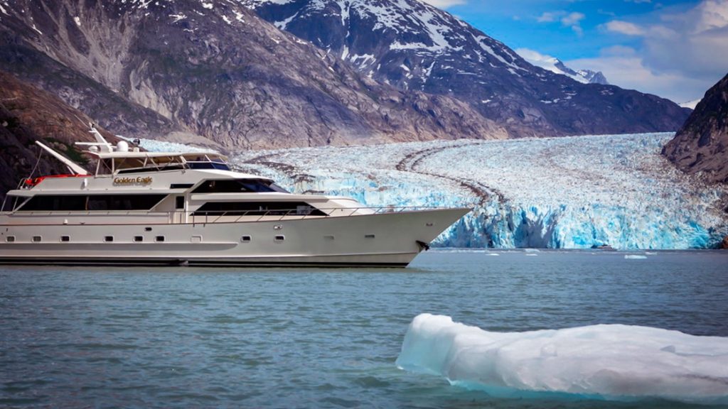Golden Eagle yacht cruising in front of Glacier in southeast Alaska with icebergs around.