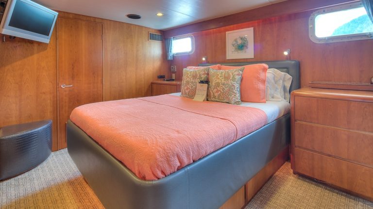 Queen cabin with dresser, bedside table, two windows, and tv on the Golden Eagle yacht.