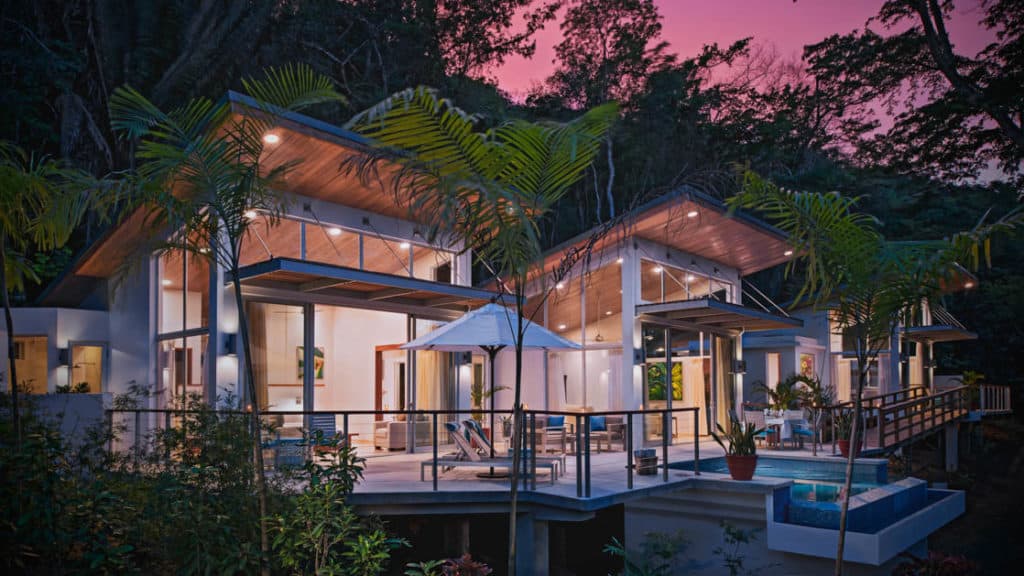 Exterior of Chaa Creek Jungle Lodge at sunset, with large indoor and outdoor living spaces surrounded by lush jungle foliage in Belize