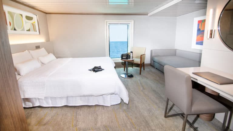 Spacious room aboard the la pinta galapagos with large bed, desk, and sofa.