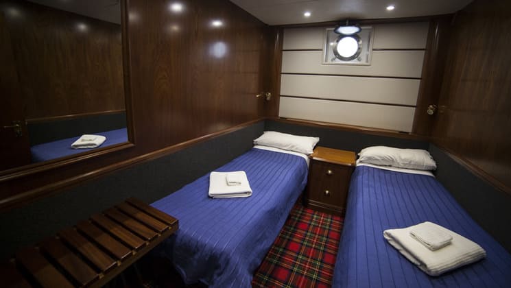 Milford Wanderer cabin with 2 twin beds, single porthole, with desk, nightstand and 2 reading lights.