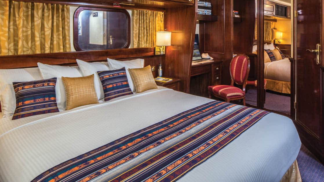 Large bed, desk, chair and window in Category 3 cabin aboard National Geographic Islander expedition ship in Galapagos Islands