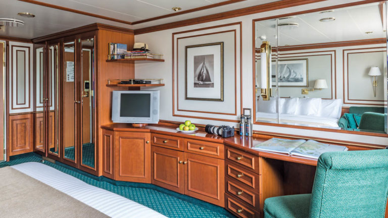 Large bed, desk, chair, TV and closet in Category 3 cabin aboard National Geographic Orion expedition ship