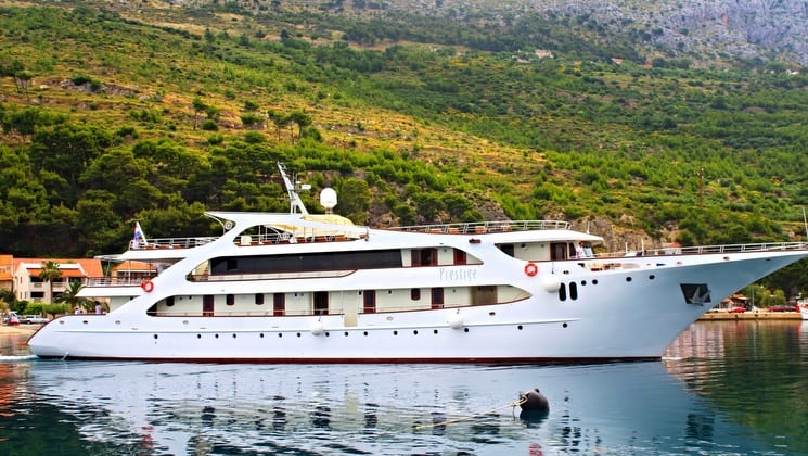 prestige luxury yacht cruising in the mediterranean with green hills in the background