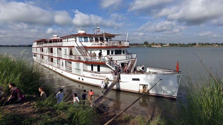 Passengers board a small ship on the mekong river, for a cruise to Vietnam and Cambodia in Southeast Asia